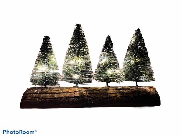 4 leuke kerstboompjes op een boomstronk met sneeuw.