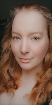 Author portrait of Sofia Yorke, author and poet, with red wavy hair and facing the xamera with a calm but soft expression.