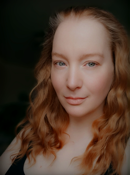 Author portrait of Sofia Yorke, author and poet, with red wavy hair and facing the xamera with a calm but soft expression.