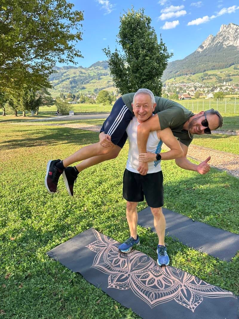 Robert Bastong, Outdoor Personal Trainer in Schwyz, trägt einen Kunden auf den Schultern, im Hintergrund die Mythen