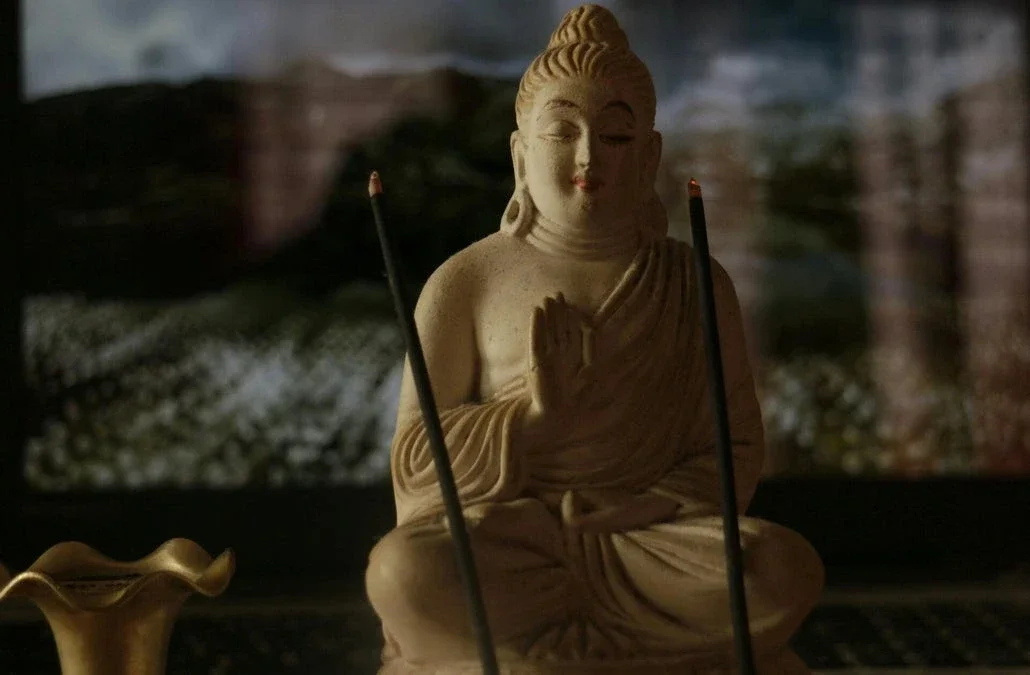 Buddha statue with incense sticks in front, symbolizing meditation, spirituality, and inner peace.