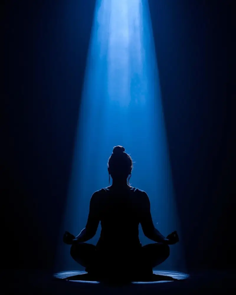 Meditation focused on inner silence, showing a calm seated figure in stillness beneath a soft blue light.