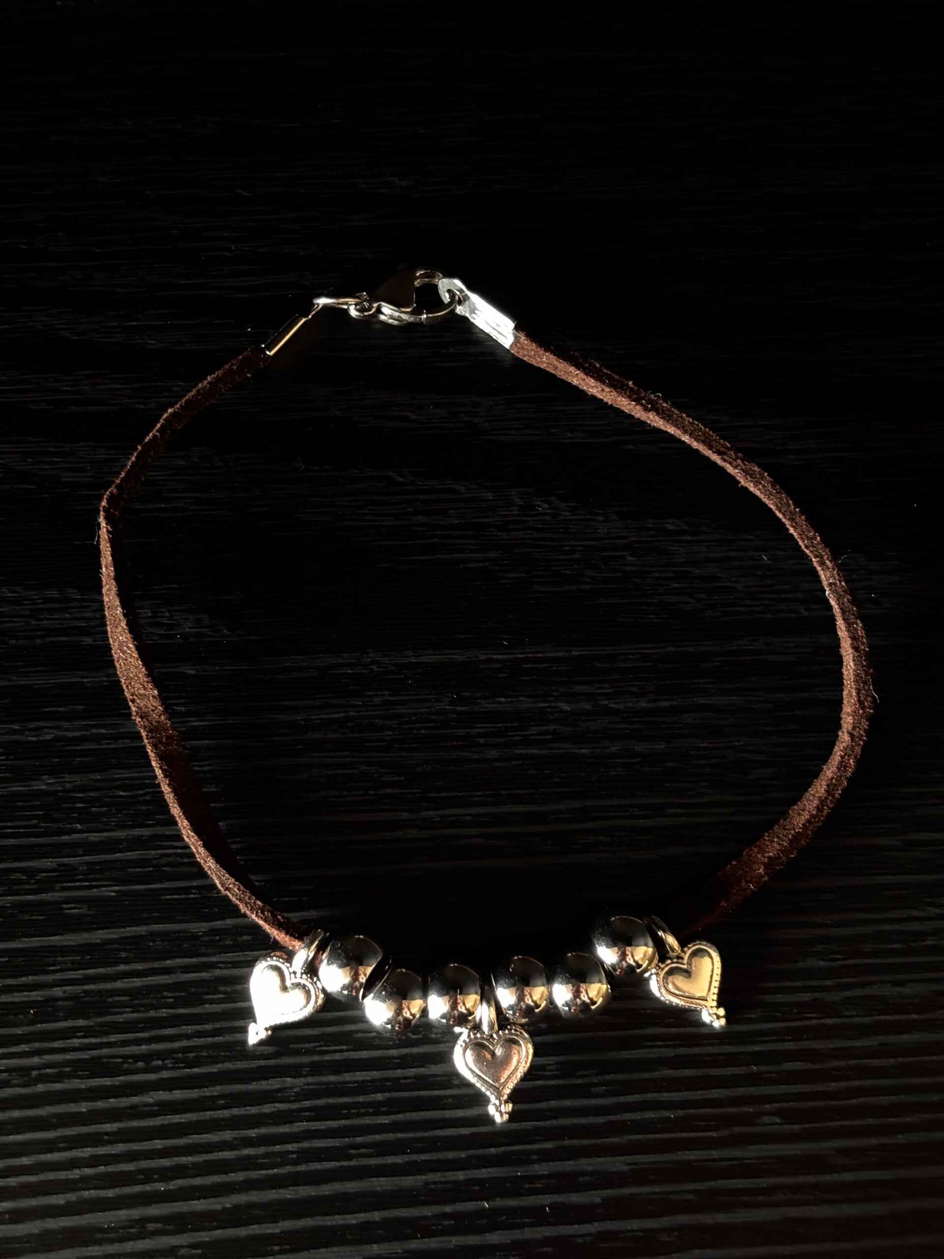Bruin suede armbandje met zilveren bedels van hartjes en ronde kralen