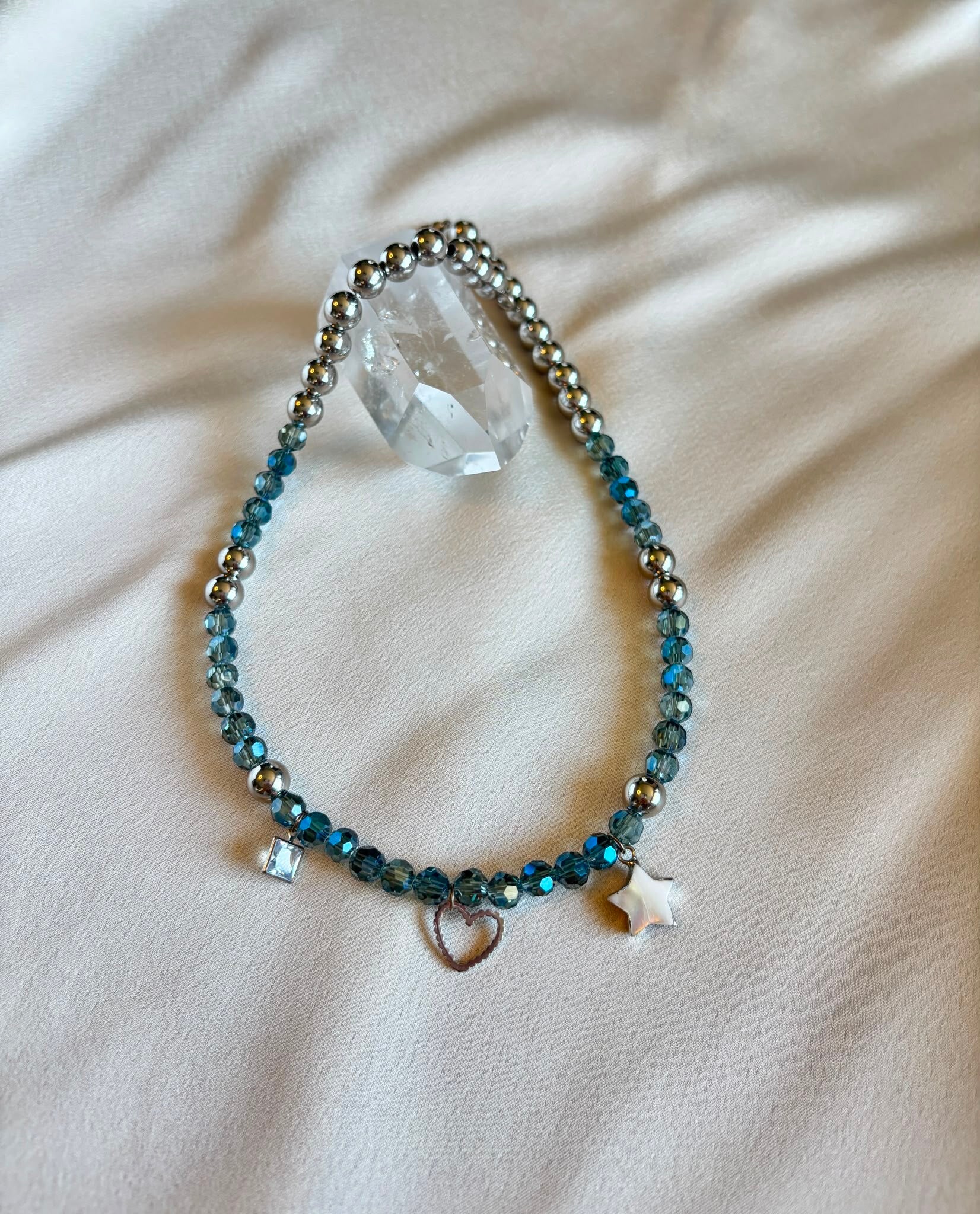 Bedelketting met 3 bedeltjes, zilveren kralen en lichtblauwe facetkralen.