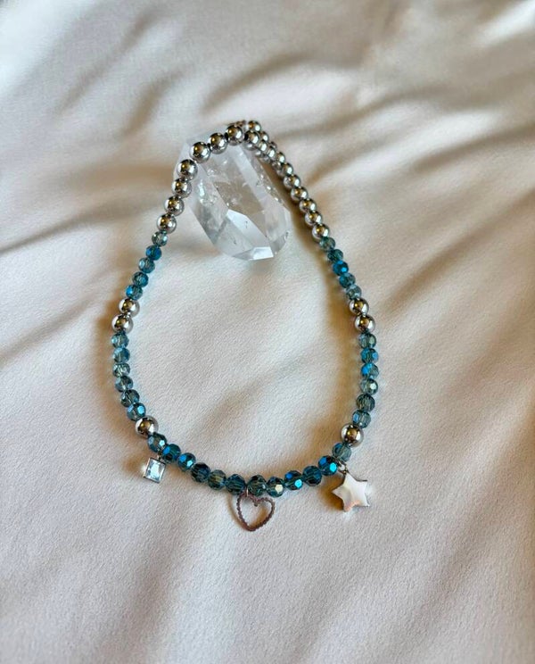 Bedelketting met 3 bedeltjes, zilveren kralen en lichtblauwe facetkralen.