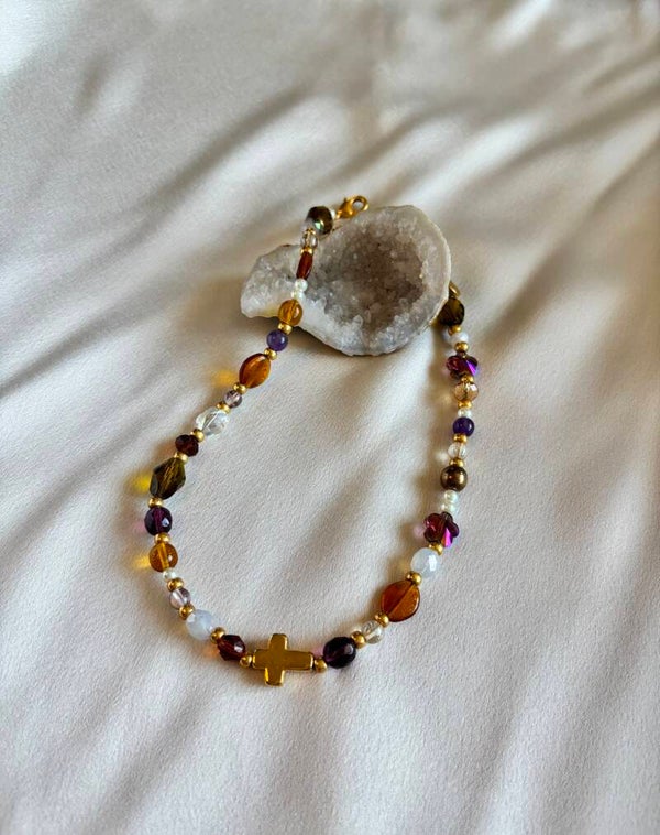 Ketting met diverse kleuren kralen en een goudkleurig kruisje
