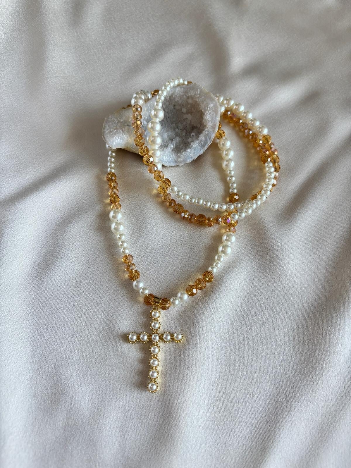 Lange ketting van parels, bruine facetkralen en een bedel van een kruis met pareltjes.