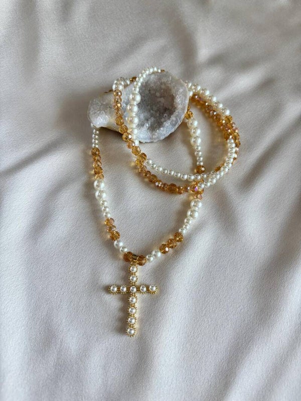 Lange ketting van parels, bruine facetkralen en een bedel van een kruis met pareltjes.