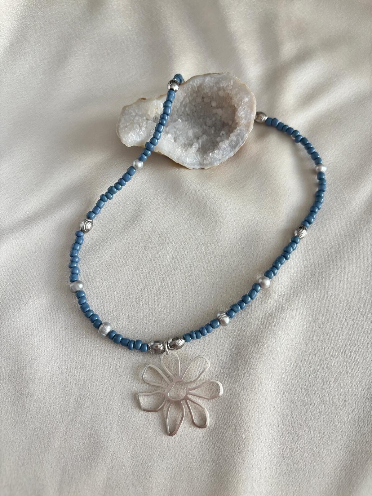 Ketting van blauwe miyuki kralen met een zilveren bloemen bedel