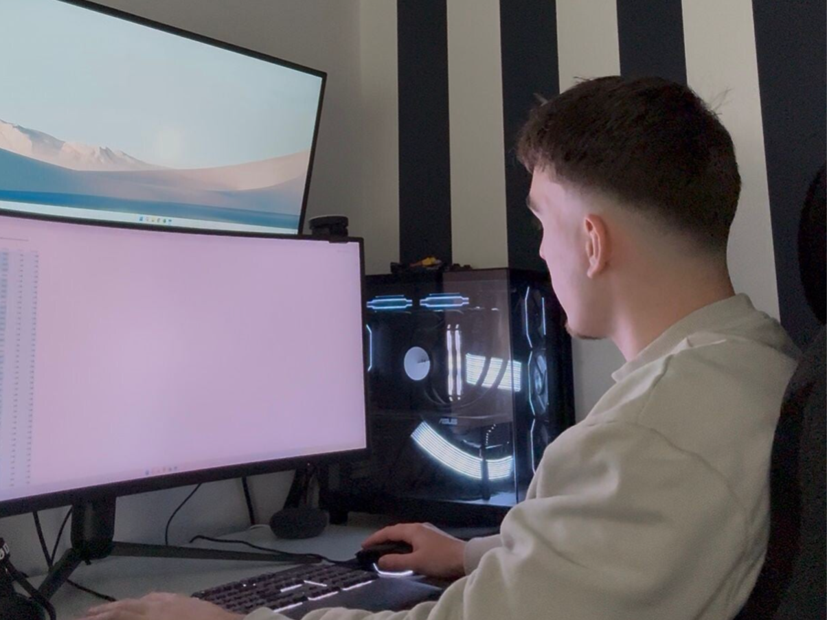 Jonge computertechnicus aan het werk achter meerdere schermen