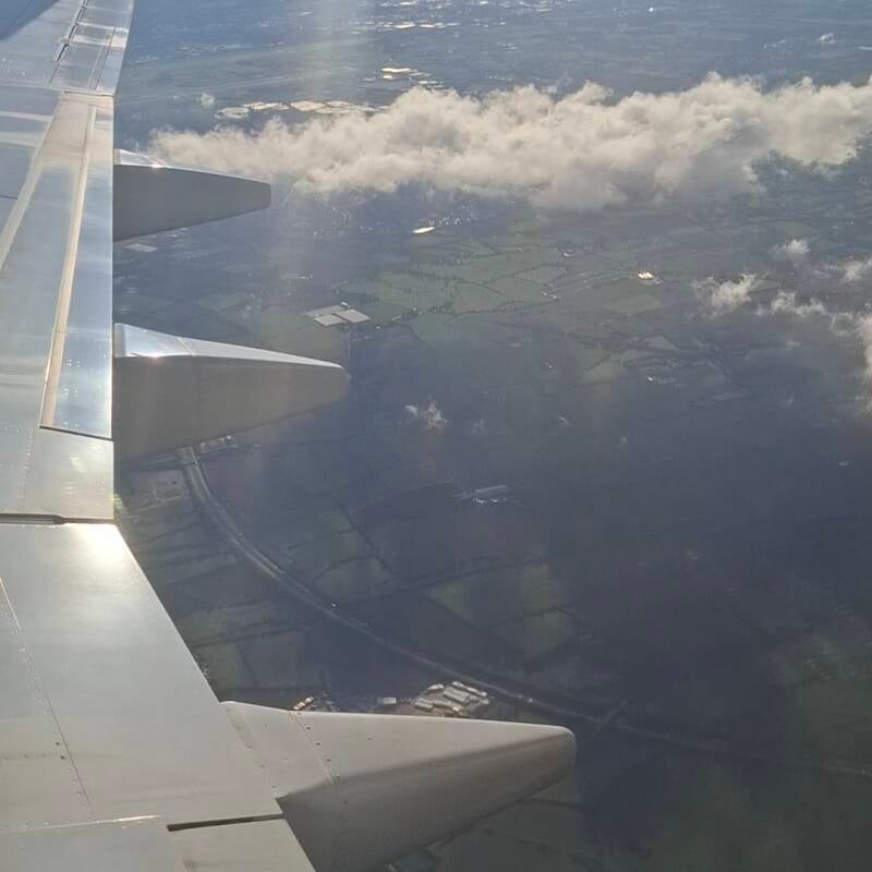 Vleugel van een vliegtuig boven de weilanden bij Amsterdam, uitzicht vanuit het raampje tijdens de landing