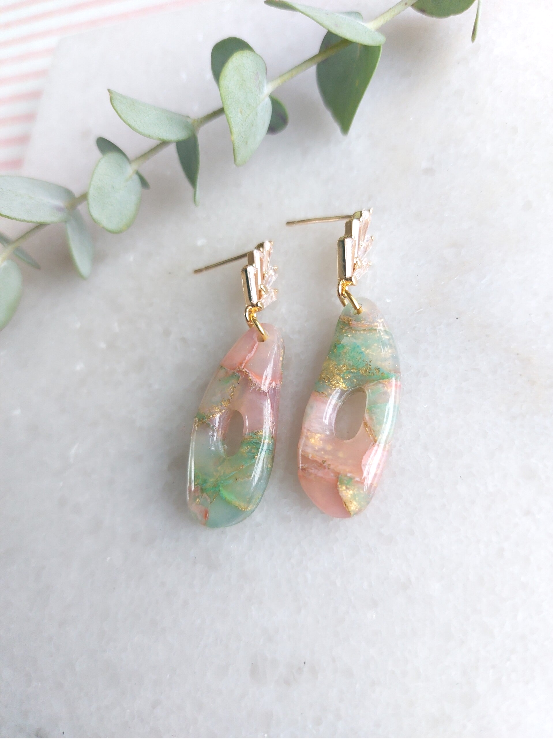 een paas ovale, opengewerkte oorbellen in zachtrood, zacht groen en doorzichtige klei, afgewerkt met een Zirkoniaknopje