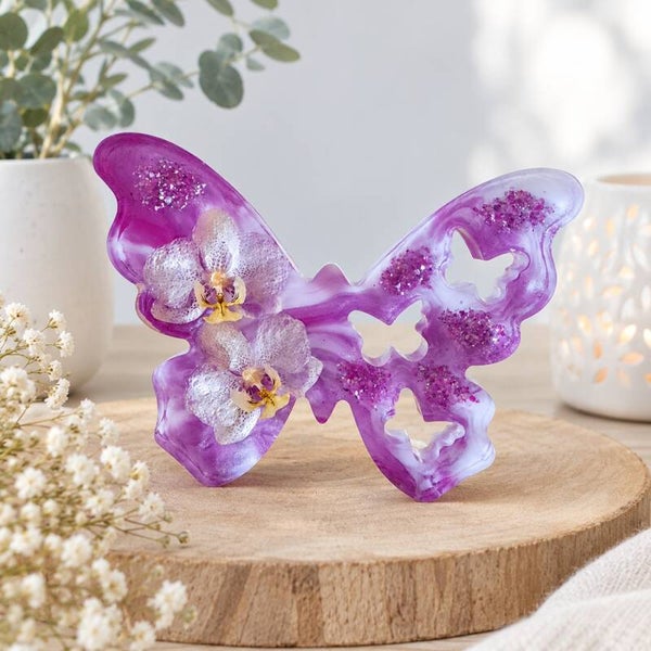 Epoxy vlinder met fuchsia-wit marmerpatroon en gedroogde orchideeën.