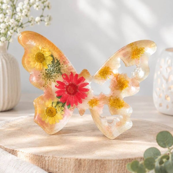 Epoxy vlinder met oranje marmerpatroon en droogbloemen.