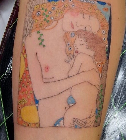 Tatuaggio colorato ispirato a Gustav Klimt che raffigura una madre che abbraccia teneramente il proprio bambino