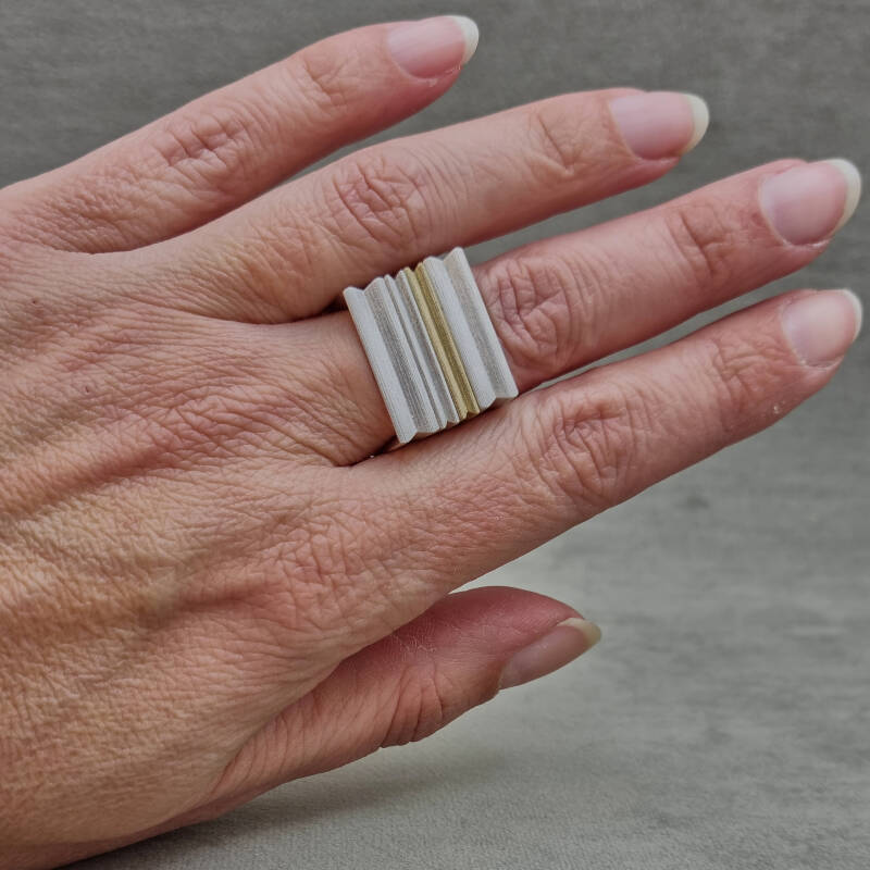 hand met twee zilveren en een gouden ring