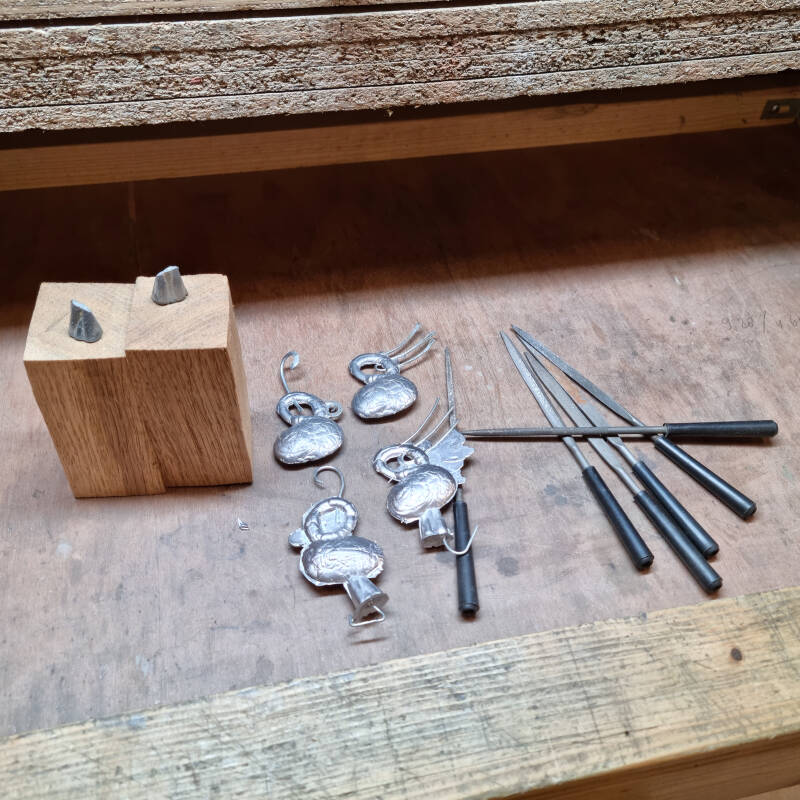 Het kapotte beeldje en de nieuwgegoten tinnen delen in het atelier