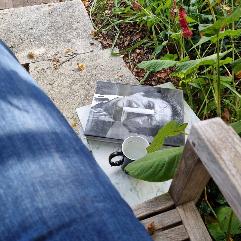 zitje in de tuin met boek over Jannis Kounellis door Gloria Moure