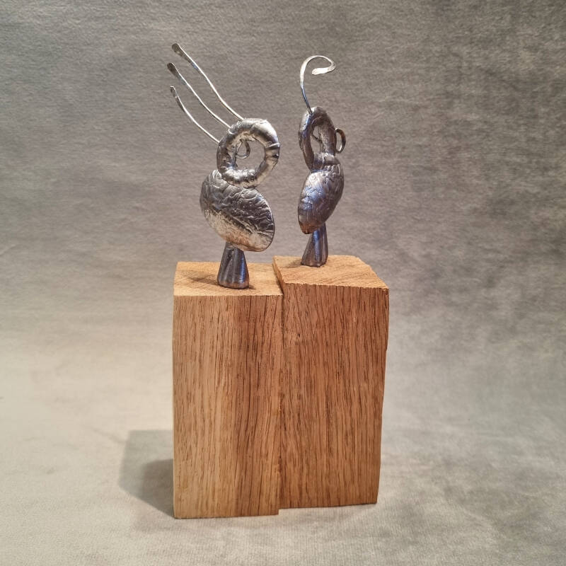 beeld met twee figuren gemaakt van tin op eikenhouten sokkel