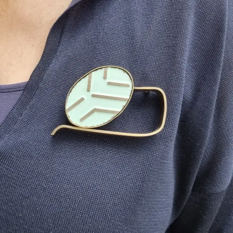 Model draagt de broche die is geïnspireerd op Slapende Muze van Constantin Brancusi, maar stelt een vraag die verder gaat dan de vorm: wie mag in de kunstgeschiedenis de rol van kunstenaar of muze claimen?