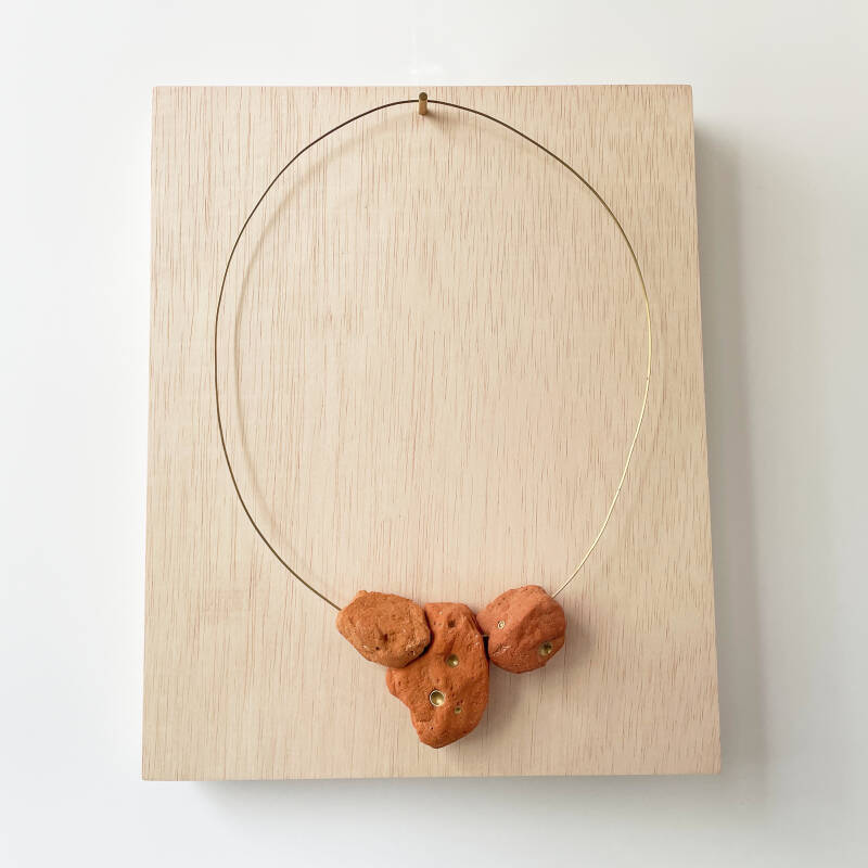 ketting van messing en baksteen gepresenteerd op doos/cq sokkel