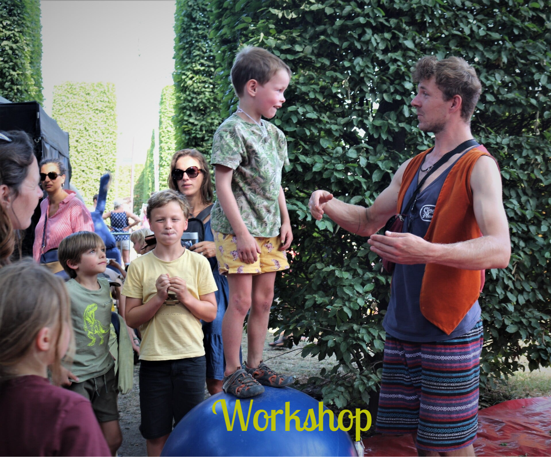 Foto van een circusworkshop tijdens de Gentse Feesten, je ziet een kind op een bal lopen en Julian van CIE Jules die enkele kunstjes uitlegd. 
