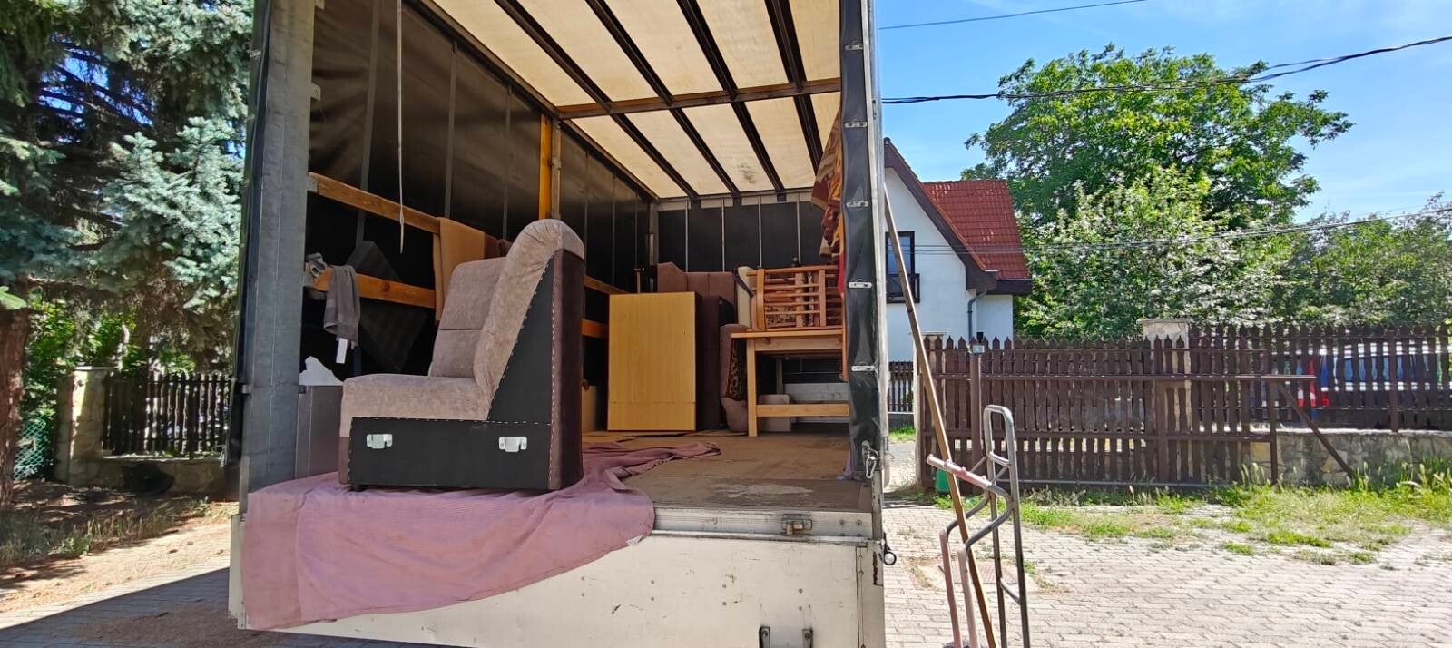 Ponyvás teherautó belülről bútorokkal, rakodás közben