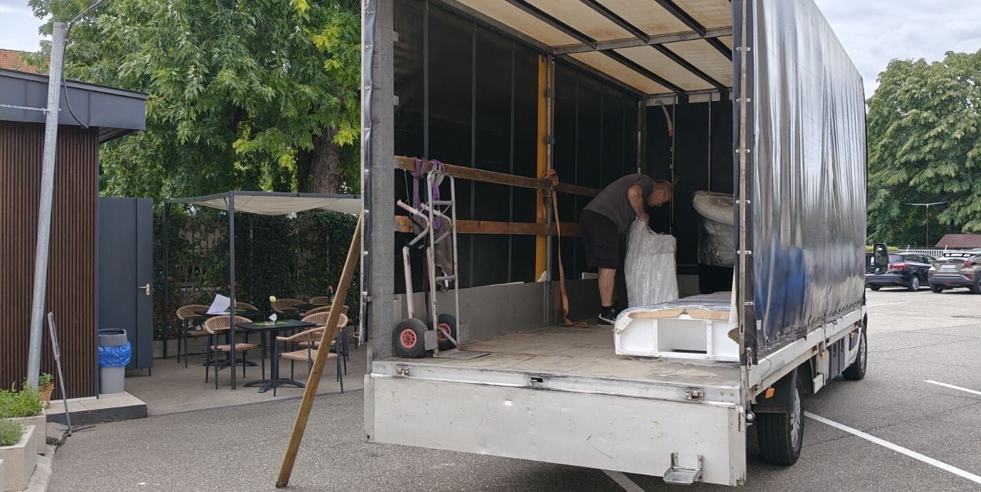 Egy férfi ponyvás teherautó platójára pakol árut