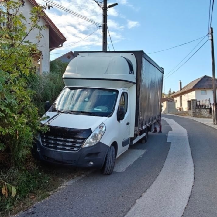 Biztosfuvar teherautó egy kertes házas övezetben parkol