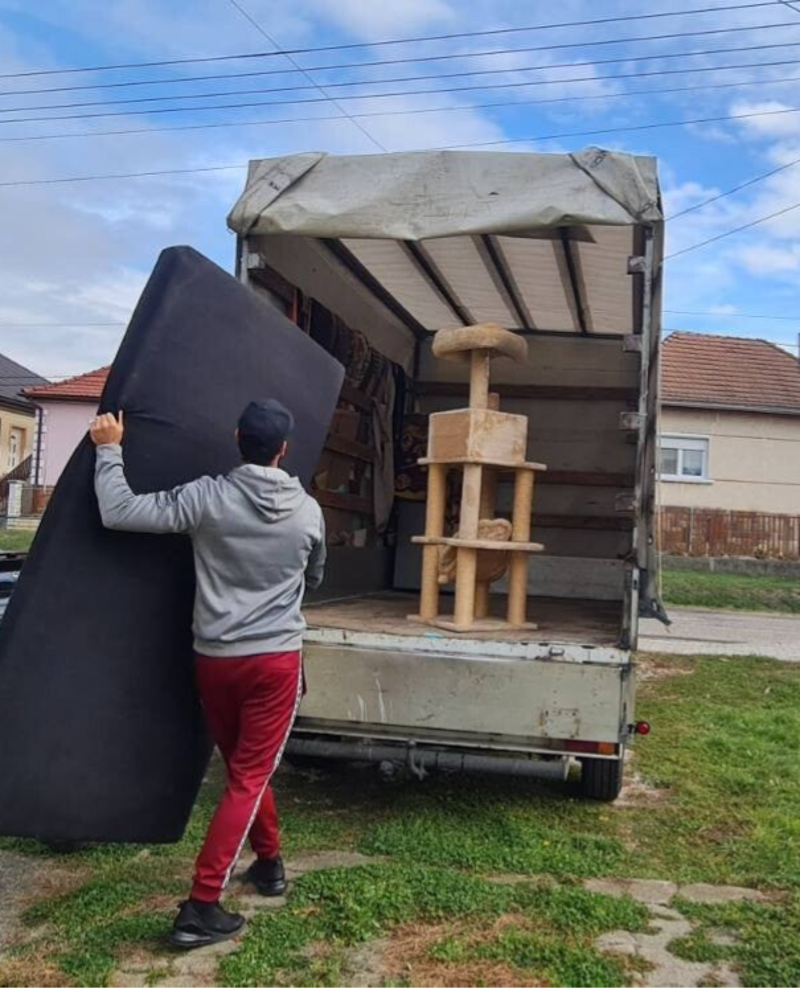 Bútorok rakodása teherautó platójára költözködéskor, egy költöztető egy matracot készül elhelyezni a költöztető autó belsejébe