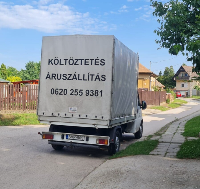 Ponyvás kisteherautó ház előtt várakozik vidéki övezetben