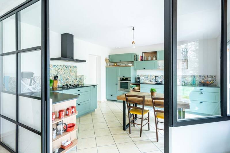 Bright kitchen with green cabinets and table.