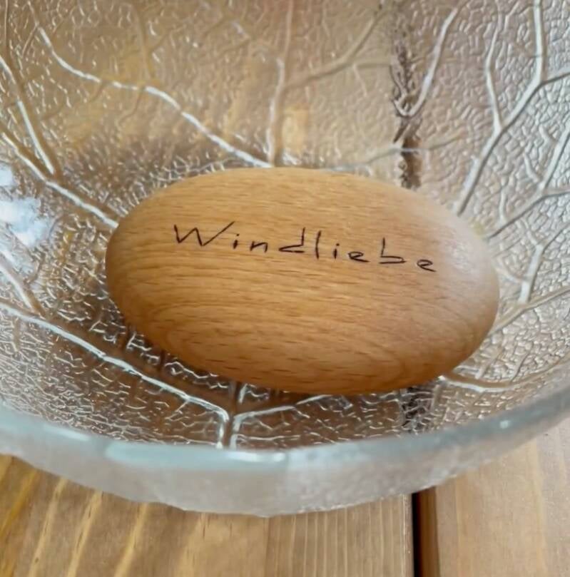 Der fertig geölte Handschmeichler liegt in einer strukturierten Glasschale – das Holz hat einen warmen, satten Farbton angenommen.