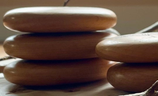 Geölte Holz-Handschmeichler, gestapelt – im warmen Gegenlicht.