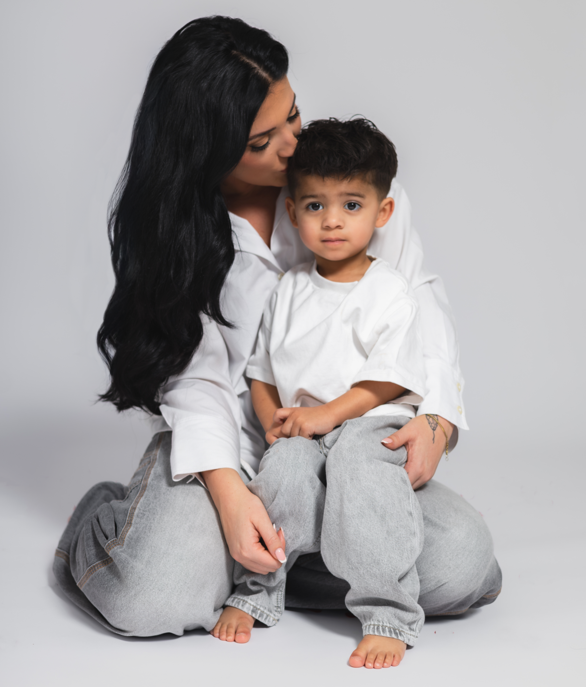 limlachend jongetje met donkere krullen op een portretfoto met zwarte achtergrond – kinderfotografie door Alyssa Dijkstra