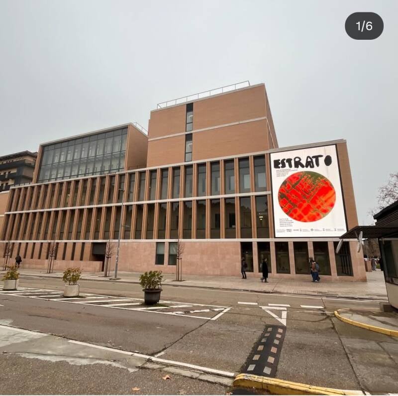 Cartel de la exposición “Estrato” de ANDAR DE NONES en la fachada de la Universidad de Zaragoza, proyecto de arte y diversidad funcional vinculado a la agenda cultural de Zaragoza.