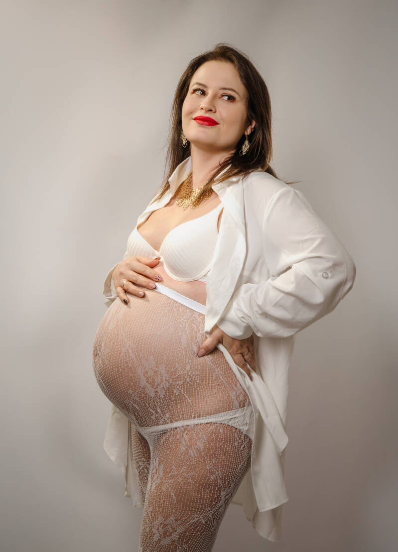 Kobieta w ciąży trzyma dłoń na brzuszku podczas profesjonalnej, sensualnej sesji ciążowej w województwie kujawsko-pomorskim