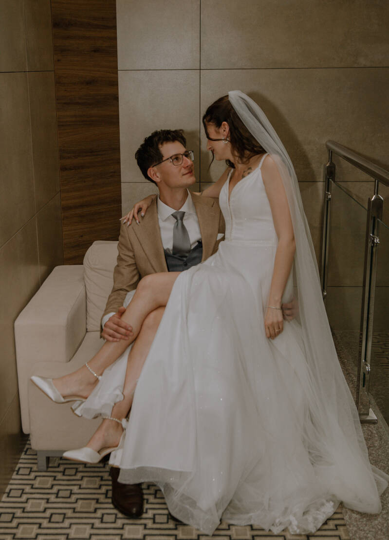 Fotograf ślubny Grudziądz i okolice – wesele i reportaż ślubny blisko Torunia i Bydgoszczy. Para młoda pozuje na hotelowym korytarzu, prezentując eleganckie stroje ślubne, wyluzowaną atmosferę i uśmiechy.