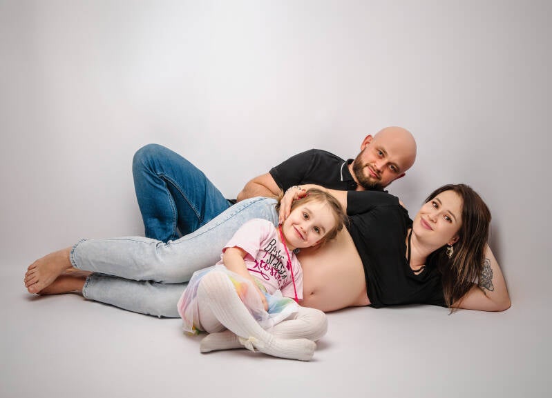Pełne luzu i miłości ujęcie Marty, Mariusza i Mai leżących w studio fotograficznym – pamiątka z sesji brzuszkowej z rodzeństwem dla klientów z okolic Torunia i Bydgoszczy