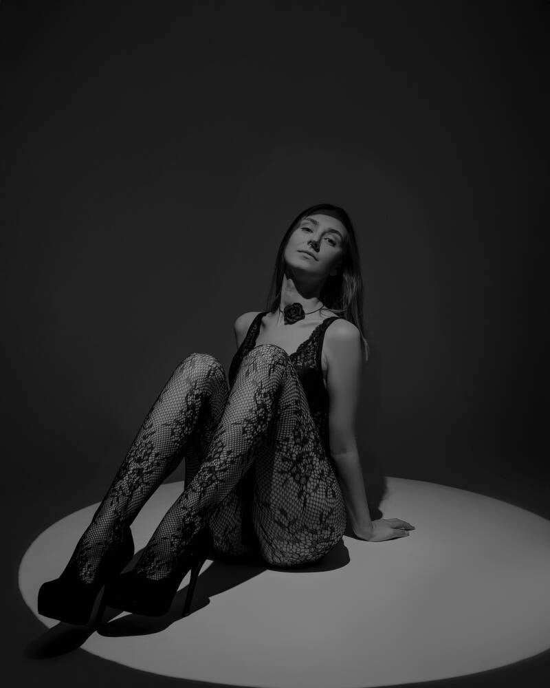 Fotografia buduarowa Grudziądz i okolice – czarno-biała sesja sensualna blisko Torunia oraz Bydgoszczy. Artystyczny portret glamour siedzącej kobiety w ciemnym studio z grą cieni