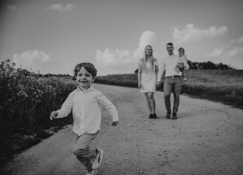 Starszy brat Ignaś uśmiecha się w biegu podczas rodzinnej sesji roczkowej na polu rzepaku – fotograf dziecięcy w województwie kujawsko-pomorskim