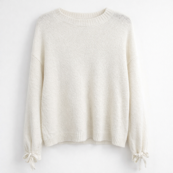 Kremowo-biały sweter o luźnym, lekko oversize’owym kroju.