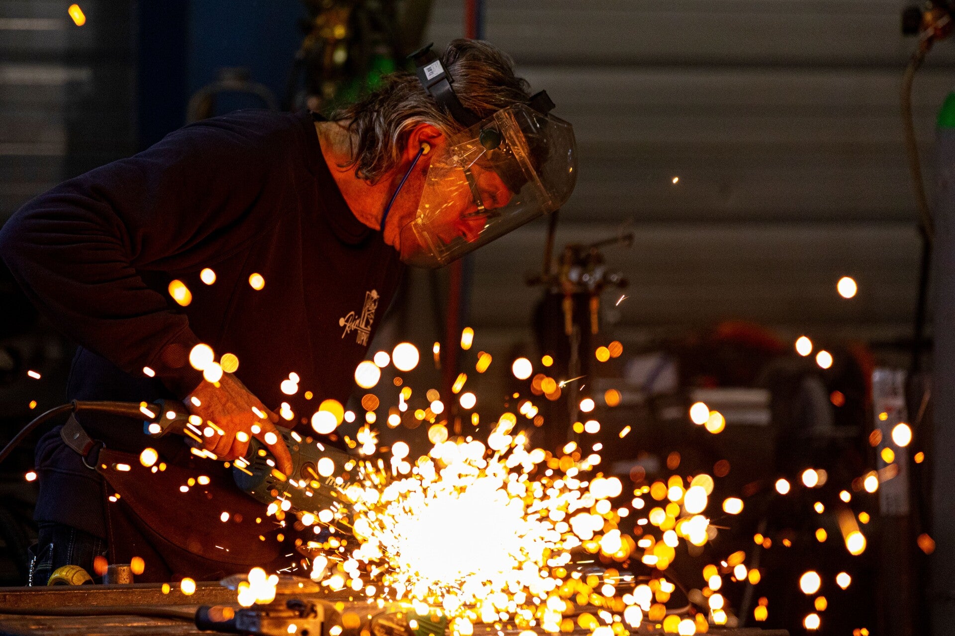 Welder cutting metal with sparks during industrial fabrication work