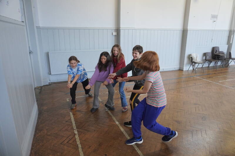 An image showing a group of people taking part in Ottery Community theatre's workshop on acting, this image shows children heaving an imaginery object from a hole