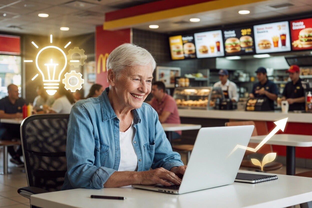 Mature woman smiling while working on laptop inside McDonald's restaurant, with idea and growth icons.