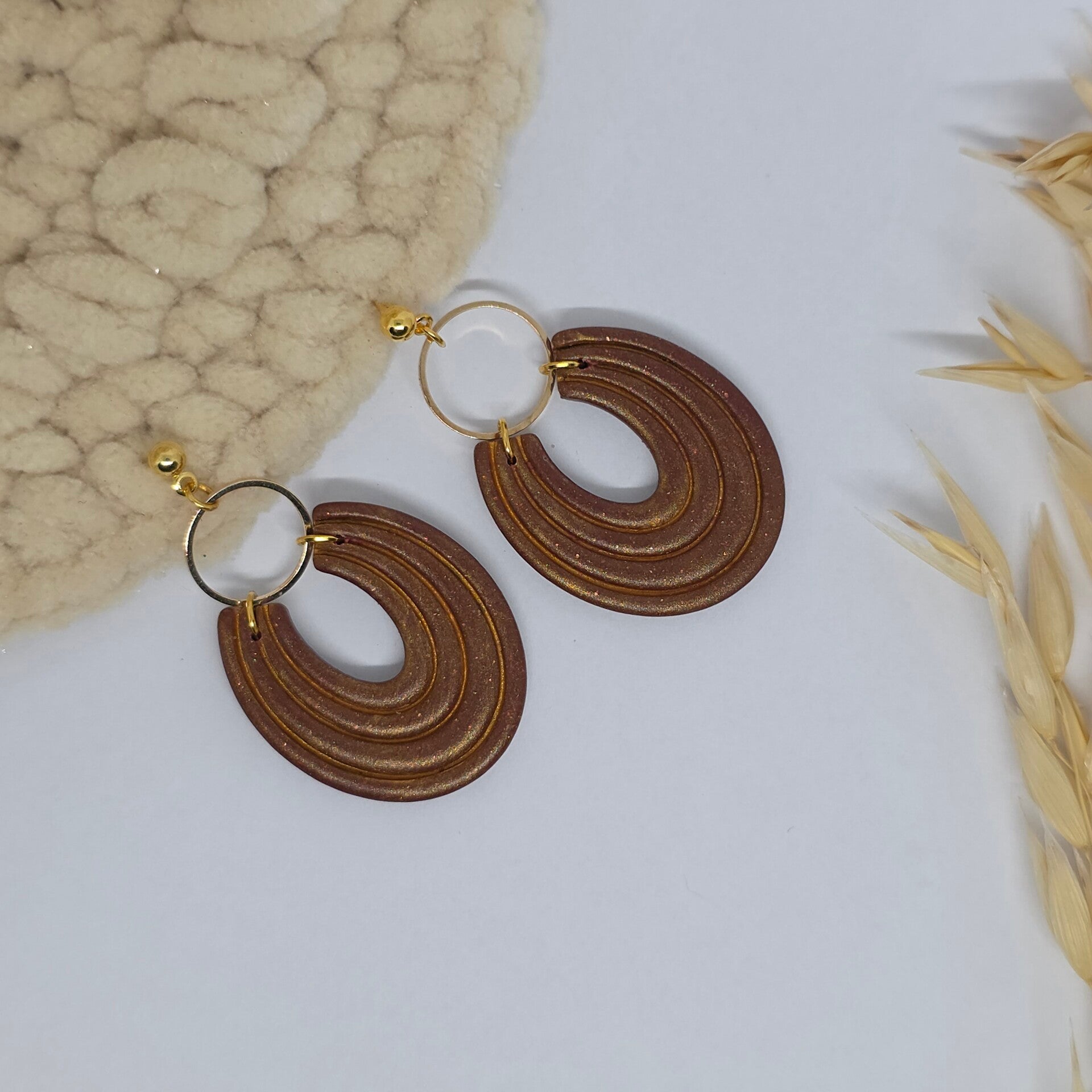 Bruin/gouden oorbellen aan oorsteker met gouden ring