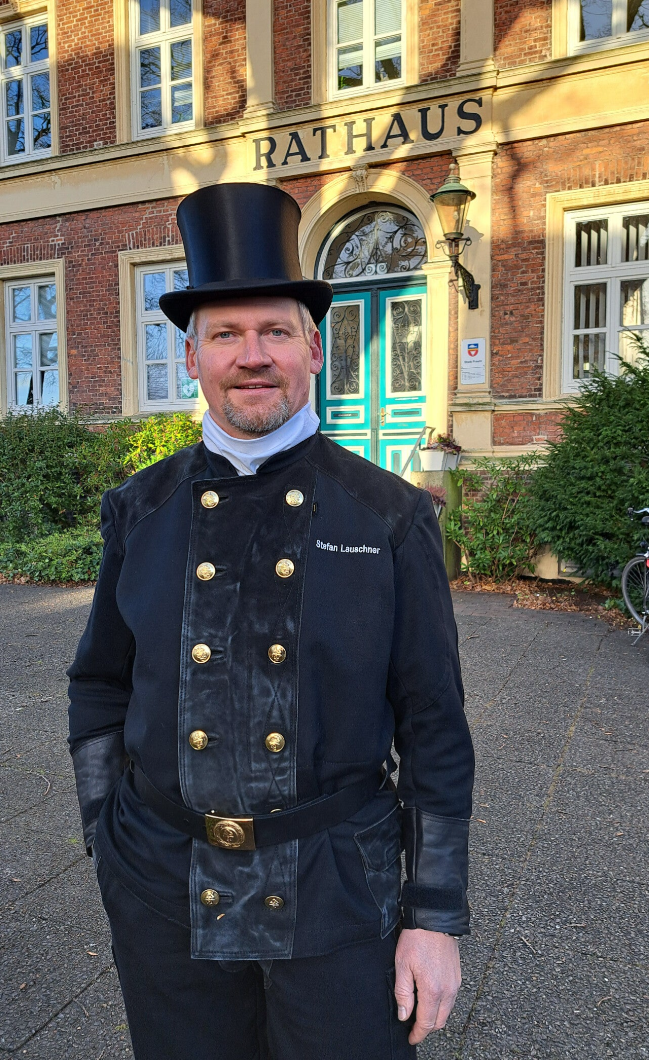 Schornsteinfegermeister Stefan Lauschner in traditioneller Kleidung vor dem Rathaus in Preetz