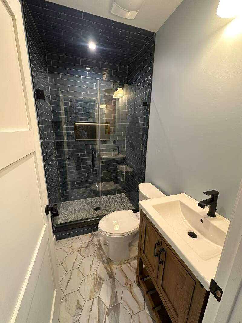 Small bathroom remodel with dark blue tile shower, wood vanity and matte black fixtures in Monmouth County NJ
