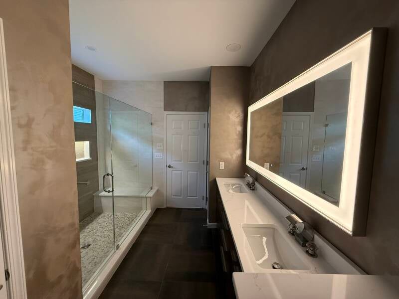 Custom walk-in shower with textured accent tile, pebble floor, built-in bench and lighted niche in Monmouth County NJ
