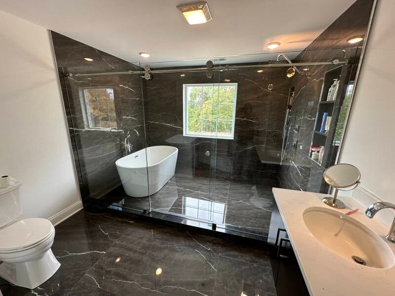 Luxury bathroom renovation with dark tile, freestanding tub and glass-enclosed shower in Monmouth County NJ
